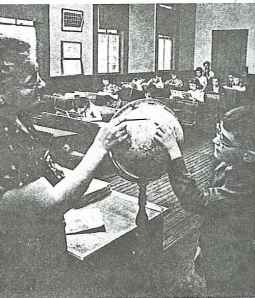 Teacher, Mrs. Mary Clark, uses the globe to explain geography.
