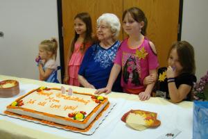 Some of Luella's grandchildren look over her 90th birthday cake.